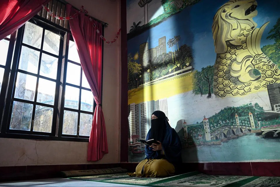 Cik Nurmayani Bensarong, 24 tahun, membaca Al-Quran di Panti Asuhan Muhammadiyah, Aceh, pada 8 Disember 2024. Sebagai penghuni panti asuhan itu sejak 2015, beliau berasa terhutang budi kepada Muhammadiyah yang telah memberikannya tempat berlindung dan pendidikan. Rasa syukur ini mendorongnya mengajar Al-Quran di Sekolah Berasrama Muhammadiyah sambil terus menetap di panti asuhan itu untuk membimbing penghuni baru, memastikan mereka mendapat sokongan dan peluang seperti yang pernah dinikmatinya.