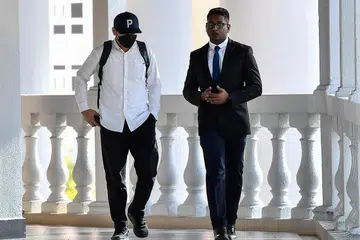 DIDAKWA MEROMPAK: Seorang tertuduh (kiri) kes merompak barangan serta wang tunai milik ahli perniagaan warga China bernilai RM1 juta ($290,000) hadir ke Mahkamah Sesyen Kuala Lumpur, pada 13 Disember 2023.