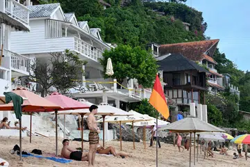 Pelancong kelihatan berada di hadapan deretan restoran yang dipasang pita sekatan polis di Pantai Bingin, kampung Pecatu, di Daerah Badung, pulau peranginan Bali, Indonesia pada 23 Julai 2025. Puluhan vila dan restoran yang dibina tanpa kebenaran rasmi daripada kerajaan telah dirobohkan oleh pihak berkuasa daerah Badung di wilayah Bali.