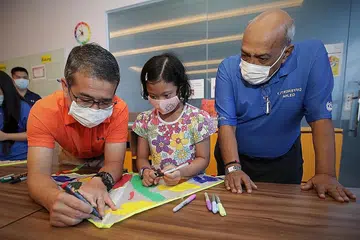 CURAHKAN PERHATIAN: Encik Edwin Tong (kiri) melukis pada layang-layang bersama penerima bantuan DSA Nur Alyssa Mohd Azli di Sekolah Rendah Opera Estate sewaktu meraikan Hari Sindrom Down Sedunia semalam.