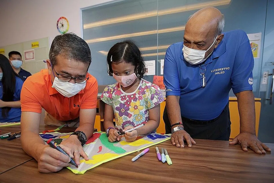 CURAHKAN PERHATIAN: Encik Edwin Tong (kiri) melukis pada layang-layang bersama penerima bantuan DSA Nur Alyssa Mohd Azli di Sekolah Rendah Opera Estate sewaktu meraikan Hari Sindrom Down Sedunia semalam.