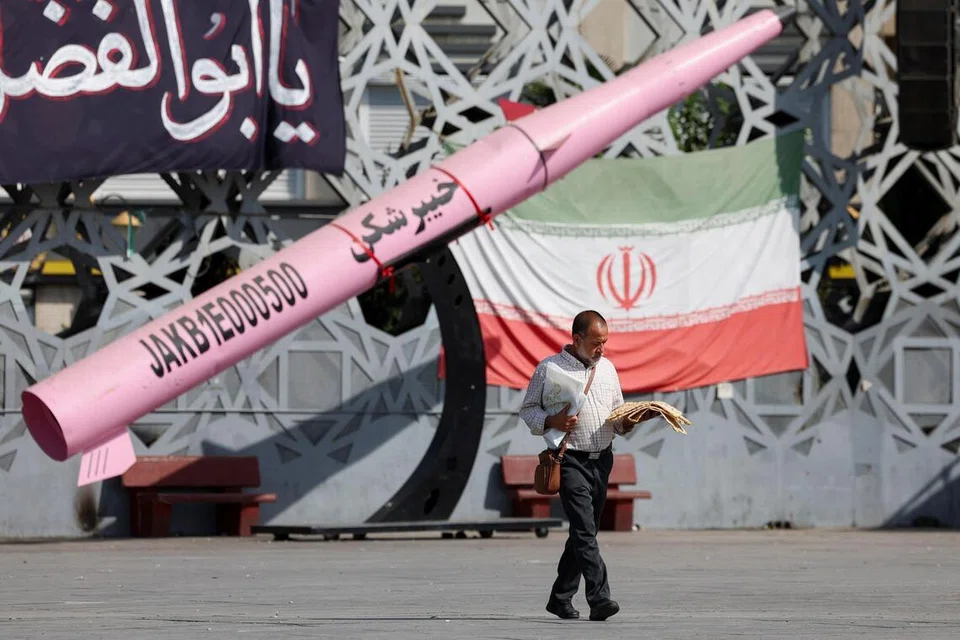 Seorang lelaki berjalan berhampiran replika simbolik peluru berpandu Iran dan bendera negara itu di Dataran Imam Hussein, Teheran, pada 12 Julai 2026. Ketika ketegangan antara Iran dan Amerika Syarikat terus memuncak, beberapa negara Teluk mengecam siri serangan balas Teheran, manakala pertikaian mengenai kawalan Selat Hormuz semakin meningkatkan kebimbangan terhadap keselamatan serantau dan bekalan tenaga dunia.