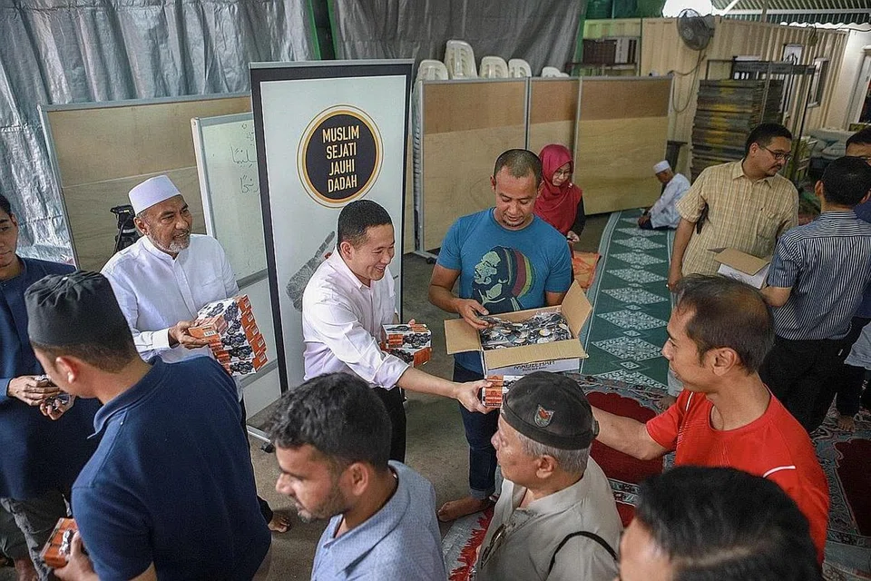 KE PANGKUAN MASYARAKAT: Encik Mohamad Riduan (dua kanan, berbaju biru) turut mengagihkan kurma bersama Encik Amrin (dua dari kiri) kepada para jemaah di Masjid Khalid kelmarin, satu cara beliau sumbang kembali kepada masyarakat. - Foto IQBAL FAIZAL