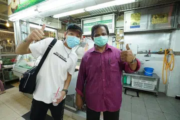 JUAL DAGING DALAM TALIAN: Encik Mohammed Mustafa (kanan) belajar menjual dagingnya di Pasar Dalam Talian Tekka daripada Encik Max Kee (di sebelahnya). - Foto IMDA