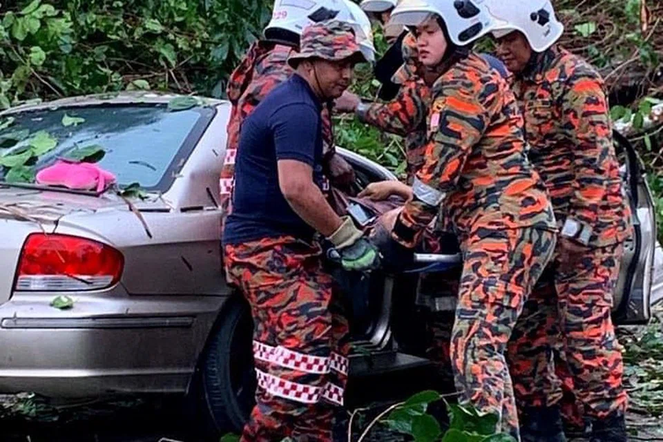 TRAGEDI MALANG: Pasukan Bomba dan Penyelamat Balai Pokok Sena keluarkan mayat mangsa yang maut akibat tersepit dalam kenderaan yang dihempap pokok tumbang di Jalan Bukit Payong, Kampung Bukit Payong, Alor Setar, Kedah.