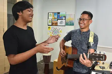 GEMBIRA DAPAT MENYANYI: Firdaus (kiri), 14 tahun, bersama pekerja kes di Creative SAY!, Encik Muhammad Syazwan Mohamed Suhri, di pusat kendalian Persatuan Kesihatan Mental Singapura (SAMH) bagi pencegahan dan kesejahteraan mental belia di Blok 317 Woodlands Street 31. Firdaus ke pusat itu hampir setiap hari untuk melepaskan tekanan. - Foto BM oleh JASMINE CHOONG