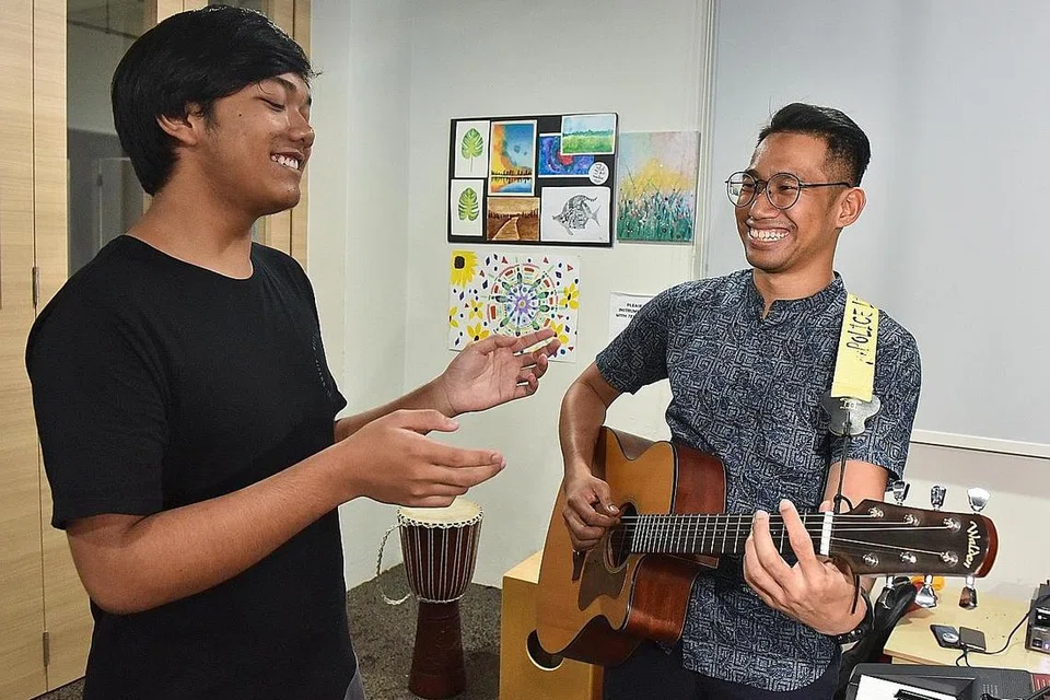 GEMBIRA DAPAT MENYANYI: Firdaus (kiri), 14 tahun, bersama pekerja kes di Creative SAY!, Encik Muhammad Syazwan Mohamed Suhri, di pusat kendalian Persatuan Kesihatan Mental Singapura (SAMH) bagi pencegahan dan kesejahteraan mental belia di Blok 317 Woodlands Street 31. Firdaus ke pusat itu hampir setiap hari untuk melepaskan tekanan. - Foto BM oleh JASMINE CHOONG