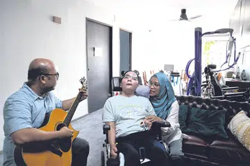 SOKONGAN KUKUH KELUARGA: Encik Razib, bersama Cik Anisah, sering bermain gitar untuk Cik Nuruljannah yang meminati muzik sebagai antara usaha menyokong pemulihan anaknya itu. - Foto MOHAMMAD RAZIB SAMSUDIN