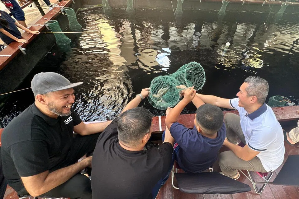 ‘Fandi’ (bukan nama sebenar), pesalah di bawah pengawasan penyelia masyarakat (dua dari kiri) bersama anaknya berusia 10 tahun (dua dari kanan) menangkap udang bersama di acara ‘Prawning with Dad’ anjuran Pusat Kebapaan (CFF) dan Bapa Sepanjang Hayat (BSH). Bersama mereka ialah relawan Bapa Sepanjang Hayat, Encik Bramsha Osman (kiri), dan penyelia masyarakat daripada Perkhidmatan Penjara Singapura, DSP Eddy Asmara Rahman (kanan).  