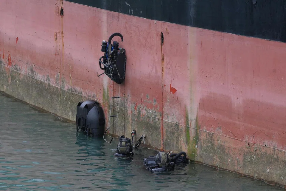 Anggota STS PCG mengerahkan robot pemanjat badan kapal Spyder (kiri).