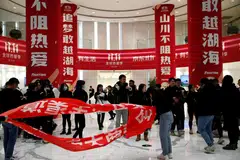 Orang ramai berdiri berhampiran sepanduk bagi pesta beli-belah ‘Singles’ Day’ di ibu pejabat JD.com di Beijing. 