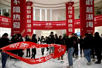 Orang ramai berdiri berhampiran sepanduk bagi pesta beli-belah ‘Singles’ Day’ di ibu pejabat JD.com di Beijing. 