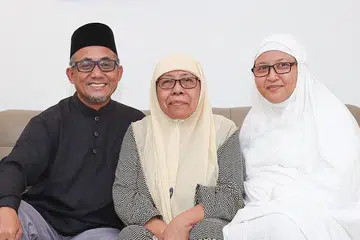 HADIAH UNTUK IBU: Cik Nurulazmi (kanan) mengetepikan $100,000 daripada Akaun Biasa (OA) CPF beliau untuk dimasukkan ke RA CPF ibunya Cik Jamilah (tengah) selepas bapanya meninggal dunia pada 2012. Bersama mereka ialah suami Cik Nurulazmi, Encik Sumri Rafe. - Foto ihsan NURULAZMI MANAN