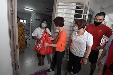 TERIMA BANTUAN: Cik Low Yen Ling (baju oren) menyerahkan barangan bantuan kepada Cik Anithashree, 52 tahun kelmarin. Seramai 775 keluarga dan pelajar rentan di Daerah South West menerima set bento beku dan pek Ceria Perayaan South West. - Foto BH oleh ALPHONSUS CHERN