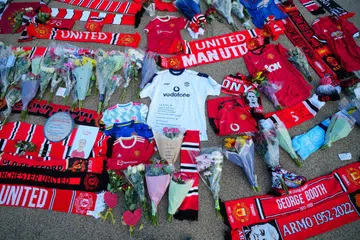 LEGENDA BOLA SEPAK: Kuntuman bunga, selempang dan kemeja-T Manchester United diletakkan di luar stadium Old Trafford di Manchester, berikutan pengumuman pemergian mendiang Sir Bobby Charlton pada Sabtu.