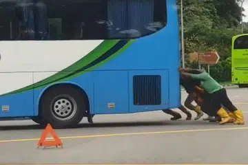 SEMANGAT KEMASYARAKATAN: Beberapa pekerja asing ini meninggalkan apa yang mereka sedang lakukan untuk bantu tolak bas rosak ini agar ia tidak menghalang lalu lintas.