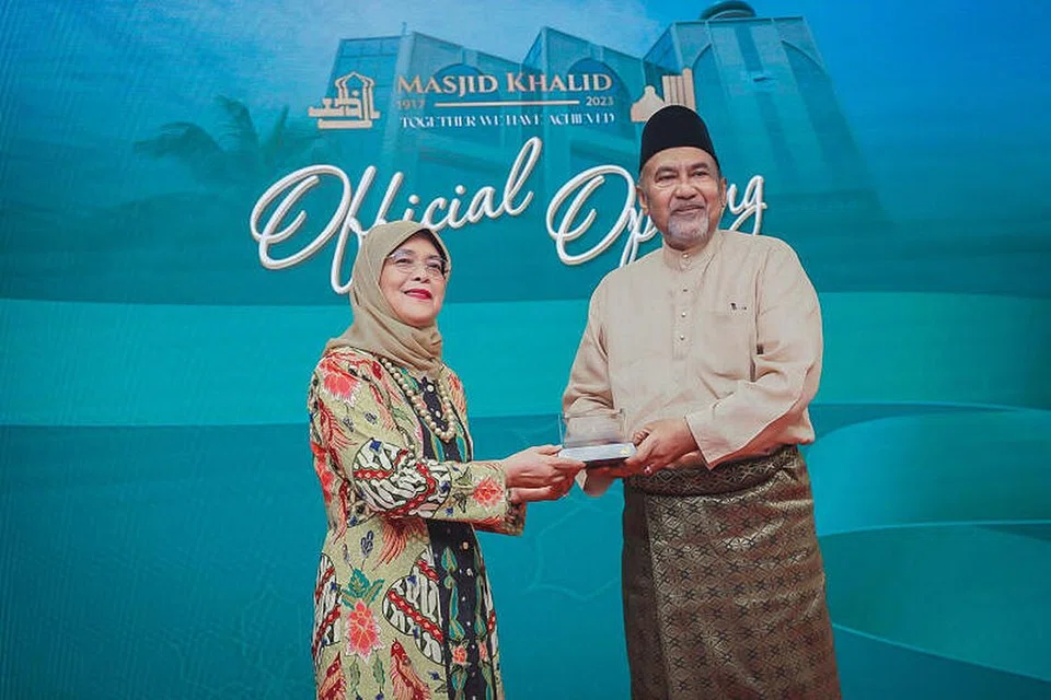 Biasiswa baru itu mengiktiraf sumbangan Encik Allaudin Mohamed (kanan) yang telah berkhidmat sebagai pengerusi Masjid Khalid selama 30 tahun. Biasiswa itu diumumkan pada Rabu di majlis pembukaan semula Masjid Khalid di Joo Chiat yang turut dihadiri Presiden Halimah Yacob (kiri).