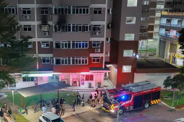 Penduduk bergegas ke tingkat bawah Blok 106, Jalan Bukit Merah, selepas api menjilat sebuah flat di tingkat empat pada 13 Ogos 2025.