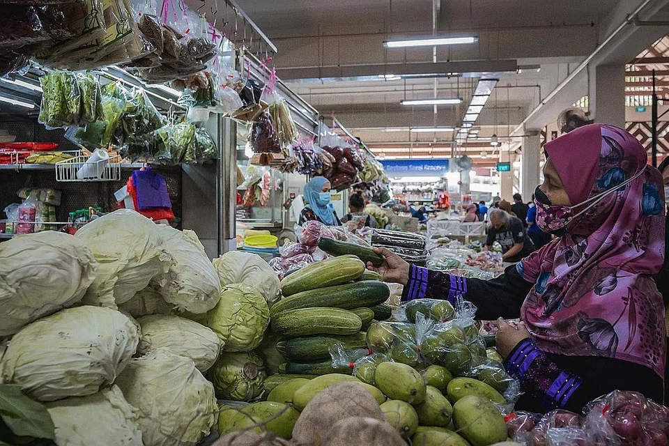 BAHAN MEMASAK: Pelanggan membeli sayur seperti timun yang dijual di Pasar Geylang Serai semalam. Banjir di Malaysia menjejas harga sayuran di sini. - Foto BH oleh NUR DIYANA TAHA