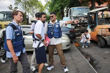 Mohd Mazuan Abdullah (tengah), diiringi polis, dibawa ke kedai alat ganti kenderaan di Sungei Kadut sekitar jam 3 petang. Dia merupakan antara tiga individu yang didakwa di mahkamah pada 16 Mac. 