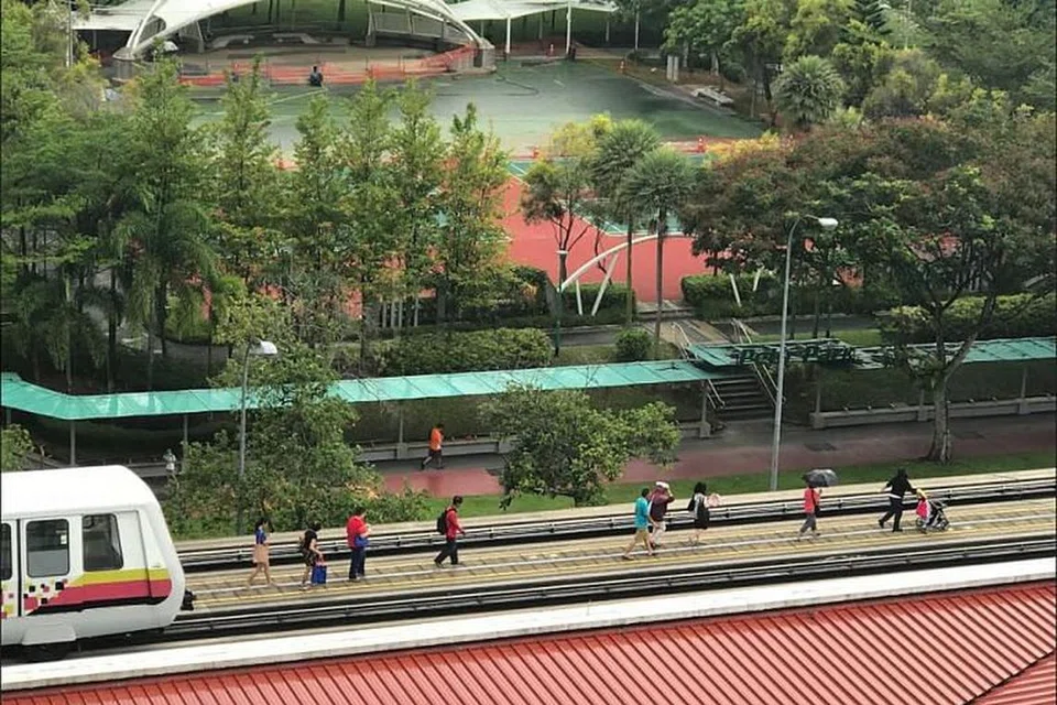 Penumpang berjalan di trek ke stesen terdekat setelah terkandas dalam sebuah gerabak LRT Bukit Panjang pada 19 Mei 2018. 