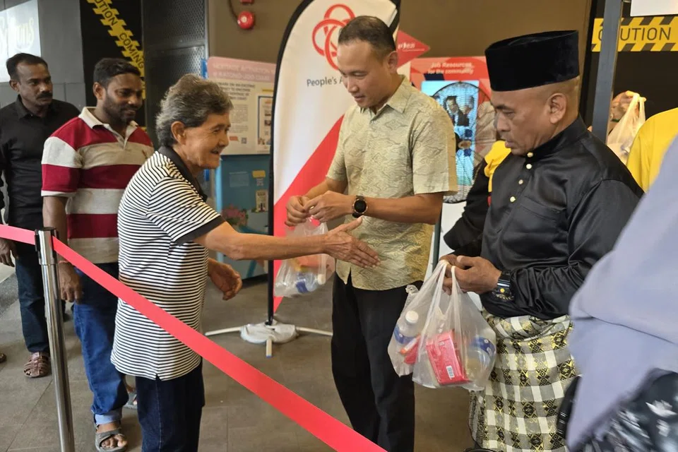 Mayor Majlis Pembangunan Masyarakat (CDC) South East, Encik Fahmi Aliman (dua dari kanan) dan pengerusi Jawatankuasa Eksekutif Kegiatan Melayu (MAEC) Geylang Serai, Encik Mohamed Zailani Mohamed Said (kanan) mengagihkan bubur kepada mereka daripada pelbagai kaum.