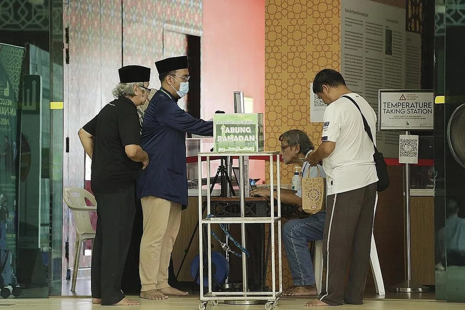 RINDU KE MASJID: Jemaah di Masjid An-Nahdhah di Bishan menjalani pemeriksaan suhu badan dan mengisi borang pengisytiharan perjalanan dan kesihatan sebelum dibolehkan menggunakan ruang solat kecil yang disediakan untuk mereka menunaikan solat zuhur. - Foto BH oleh AZMI ATHNI