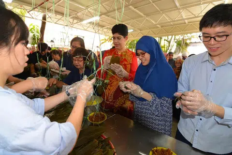 ERATKAN IKATAN: Dr Fatimah Lateef (tengah) bersama peserta berlainan agama bersama membuat kuih cang sempena Pesta Kuih Cang Berbilang Kaum. - Foto THE STRAITS TIMES