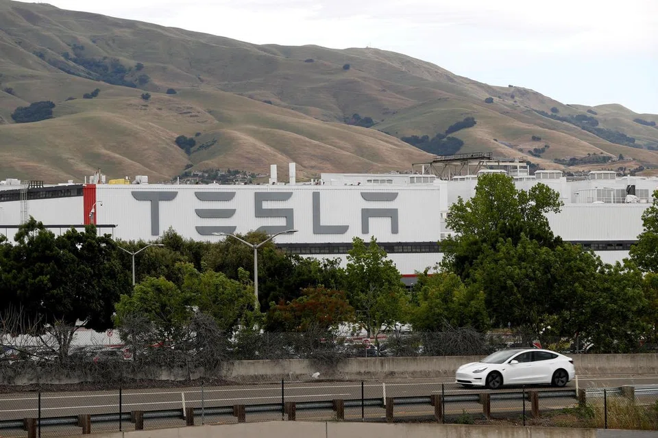 Sebuah kenderaan Tesla kelihatan melintasi kilang kenderaan utama Tesla di Fremont, California.