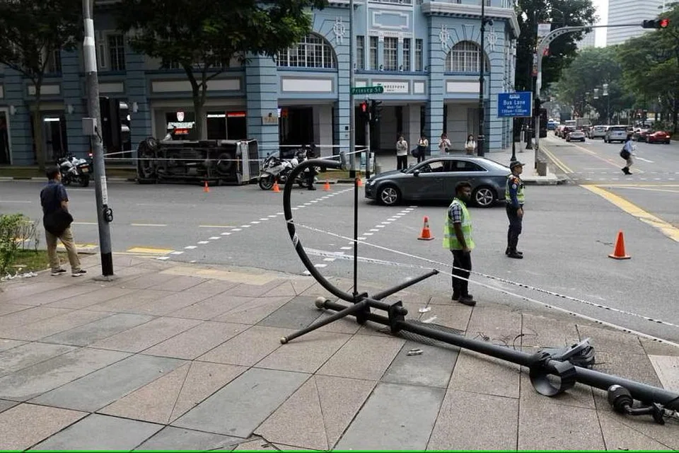 TIANG LAMPU TUMBANG : Pemandu melanggar tiang lampu sebelum lori terbaring di tepi jalan.