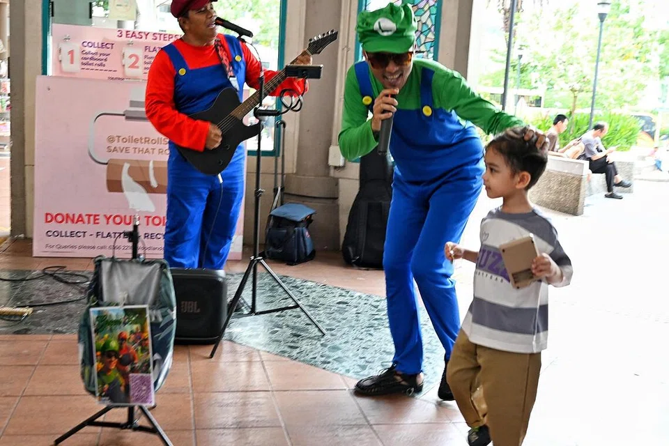 Duo ‘Green Band’ berinteraksi dengan kanak-kanak ketika membuat persembahan jalanan.