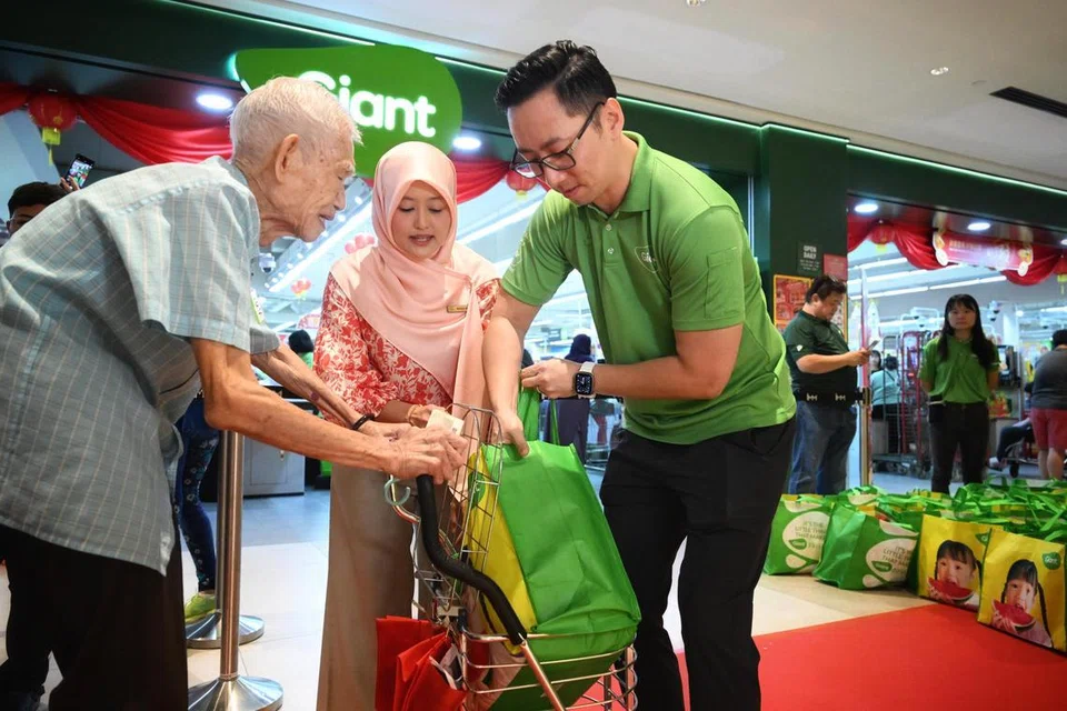 (Dari kiri) Encik Lai Yin Meng, 90 tahun, menerima beg berisi barangan keperluan isi rumah daripada Menteri Negara (Penerangan dan Pembangunan Digital merangkap Kesihatan), Cik Rahayu Mahzam,  dan pengarah urusan makanan di DFI Retail Group di Singapura, Encik Yoep Man, di pasar raya Giant di pusat beli-belah IMM Mall pada 4 Januari.
