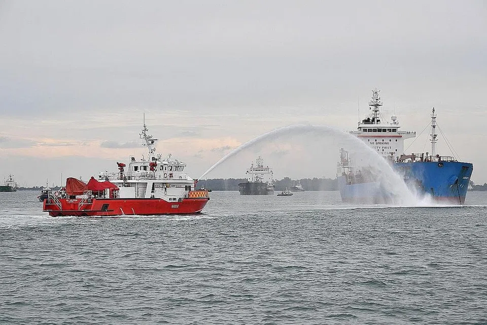 LATIHAN TUMPAHAN MINYAK: Kapal tangki minyak (kanan) yang menumpahkan minyak disimbah air oleh kapal Mass Rescue Vessel dan Rapid Response Fire Vessel SCDF sewaktu latihan tumpahan minyak secara bersama semalam. - Foto BH oleh CHONG JUN LIANG