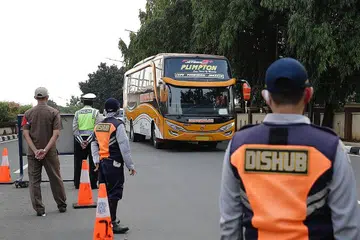 KAWALAN KETAT: Sebuah bas tiba di pusat pemeriksaan di Jakarta, kelmarin. Pemerintah Indonesia melaksanakan sekatan perjalanan sepanjang perayaan Aidilfitri antara 6 hingga 17 Mei dalam satu usaha mengekang penularan jangkitan dalam kalangan masyarakat. - Foto EPA-EFE