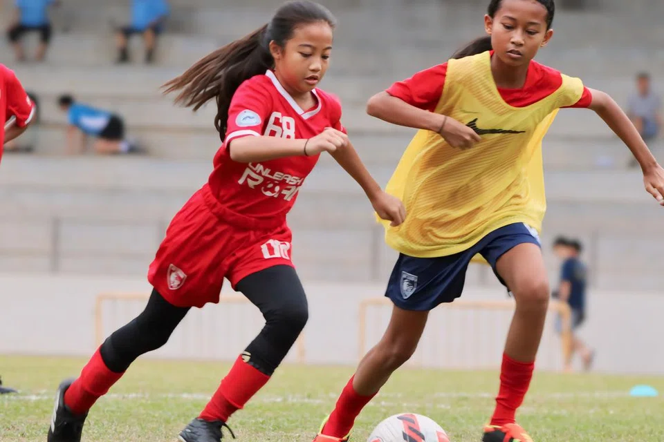Nufah Asyura Mohamad Hisham (kiri), 12 tahun, berlatih bersama pasukan Pusat Pembangunan Nasional (NDC) U-13, dan mewakili mereka dalam Liga Belia Singapura.