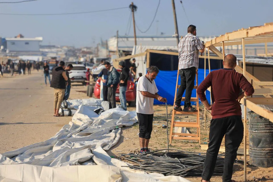 PERLINDUNGAN SEMENTARA: Penduduk Palestin yang kehilangan tempat tinggal dan melarikan diri dari Khan Yunis, membina tempat perlindungan sementara di sebuah kem di Rafah di selatan Semenanjung Gaza pada 4 Disember 2023.