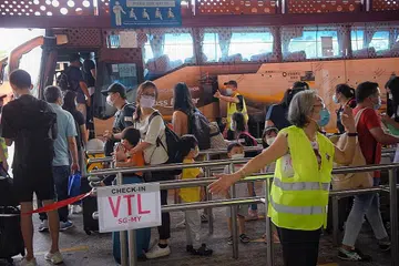 BERI KHIDMAT: Seorang kakitangan Transtar Travel kelihatan mengarahkan penumpang menuju ke Malaysia menerusi VTL di Pusat Pertukaran Bas Sementara Woodlands pada 20 Disember 2021. - Foto fail