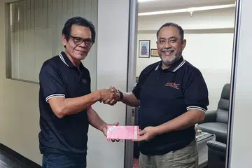USAHA MURNI: Pengarah Urusan Pos TKI Services Ptd Ltd, Encik Mohamed Anwar Tahar (kanan), menghulurkan derma menerusi cek berjumlah $10,000 kepada Presiden Prihatin, Joe Jasmi, sebagai membantu artis dan seniman Melayu Singapura yang sakit, uzur dan memerlukan bantuan pada Jun lalu. - Foto PRIHATIN SINGAPURA