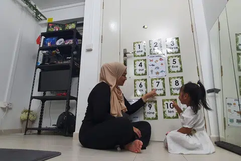 Dalam usaha mendidik anak perempuannya, Laila, Cik Aini (kiri) memanfaatkan ruang di rumah sewanya dengan menampal kad nombor di bahagian belakang pintu, membantu Laila belajar mengira dari satu hingga sepuluh.