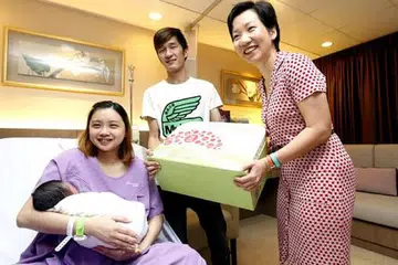 BAYI PERTAMA 2015: Cik Fu (kanan) menyampaikan Hadiah Bayi Jubli SG50 kepada pasangan Cik Lian Wen Fang dan Encik Tham Kuan How yang anaknya, Chloe Tham dilahirkan tepat pada 12 tengah malam. - Foto THE STRAITS TIMES