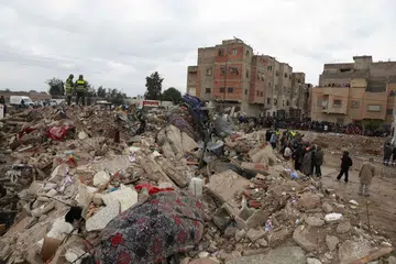 Orang ramai berdiri berhampiran lokasi dua bangunan runtuh di kawasan Al Massira di Fes pada 10 Disember 2025. Dua bangunan setinggi empat tingkat itu runtuh di bandar Fes, Maghribi, mengorbankan sekurang-kurangnya 22 orang, menurut agensi berita negara pada 10 Disember. 