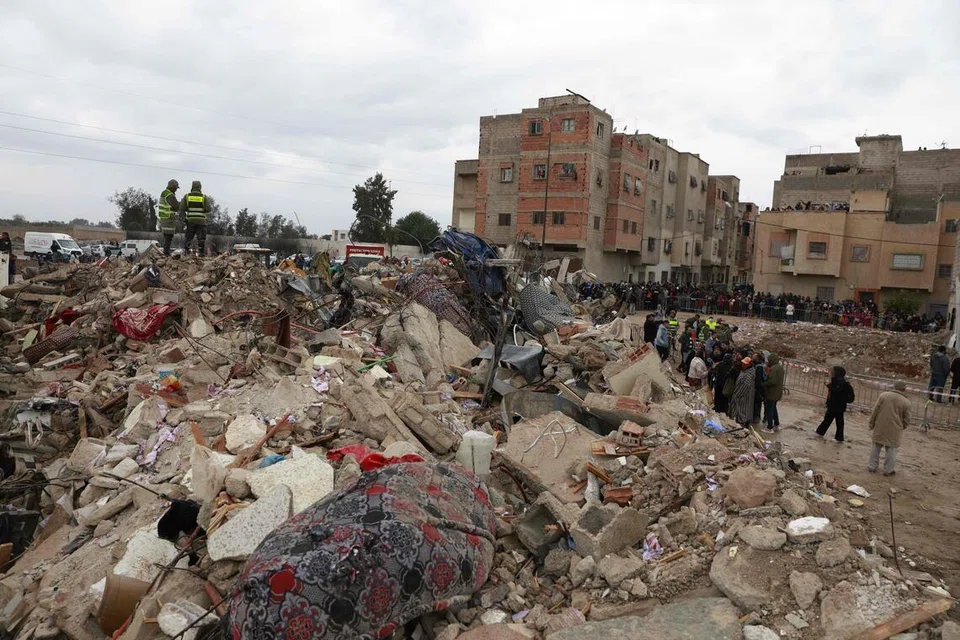 Orang ramai berdiri berhampiran lokasi dua bangunan runtuh di kawasan Al Massira di Fes pada 10 Disember 2025. Dua bangunan setinggi empat tingkat itu runtuh di bandar Fes, Maghribi, mengorbankan sekurang-kurangnya 22 orang, menurut agensi berita negara pada 10 Disember. 