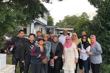 HULURKAN TANGAN BANTU SESAMA INSAN: Cik Suzana Samsudin (empat dari kanan) dan suaminya, Encik Mohd Zali Kamari (berbaju putih, berdiri di belakang), bersama rombongan dari Auckland ketika menziarah sebuah keluarga asal Singapura yang turut membantu menyediakan makanan untuk keluarga mangsa serangan. - Foto ihsan SUZANA SAMSUDIN