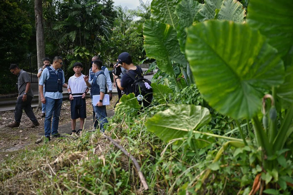Wu Jinxing (kemeja-T putih) membawa polis ke tapak simpan barang curi pertama di Koridor Kereta Api, yang juga tempat suspek ditahan polis pada 27 Julai.  
