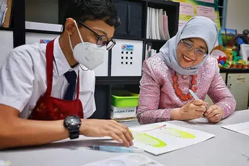 LAWAT SEKOLAH: Presiden Halimah Yacob menyertai kelas seni bersama pelajar, Muhammad Hadi Azim Azhar, 14 tahun, semasa lawatannya di Sekolah Tanglin pada Selasa. - Foto ST