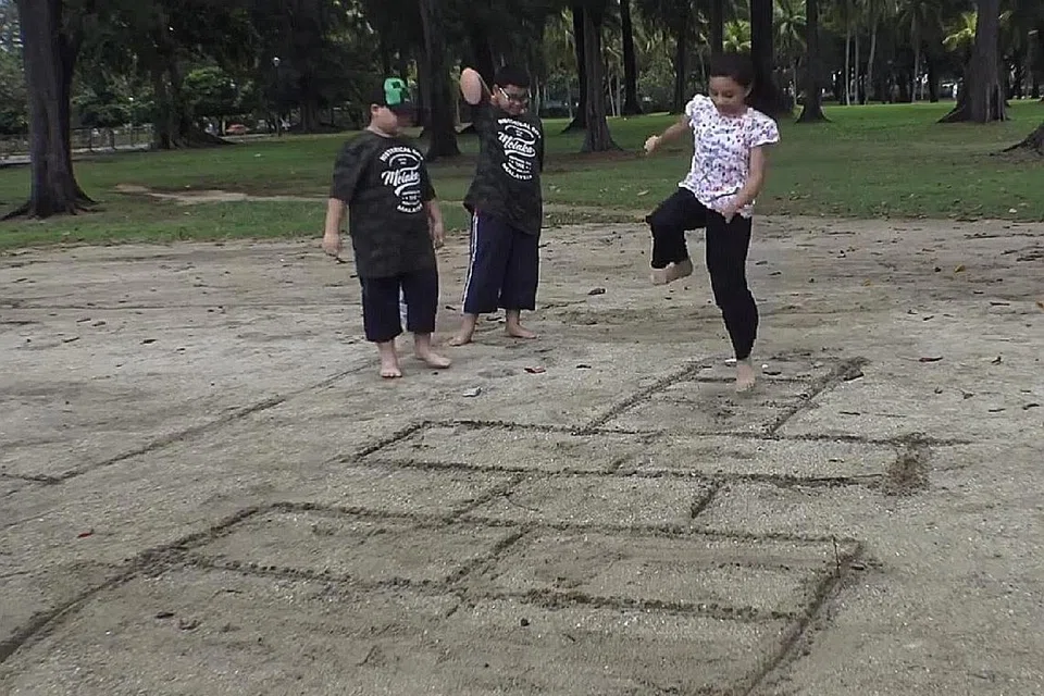 PERMAINAN TRADISIONAL: Majlis Pusat telah bergabung dengan M3@ Woodlands, MAEC Sembawang, Jawatankuasa Pembelajaran dan Penggalakan Penggunaan Bahasa Melayu (MLLPC) dan Lembaga Warisan Negara (NHB) untuk menerbitkan video mengenai Permainan Anak Kampong. - Foto tangkap layar video MAJLIS PUSAT