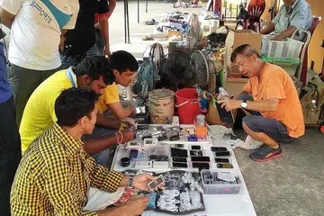 TAWAR MENAWAR: Seorang pegerai melayan pelanggan, kebanyakannya pekerja asing, yang rancak tawar-menawar ketika membeli telefon bimbit terpakai. - Foto SAINI SALLEH.