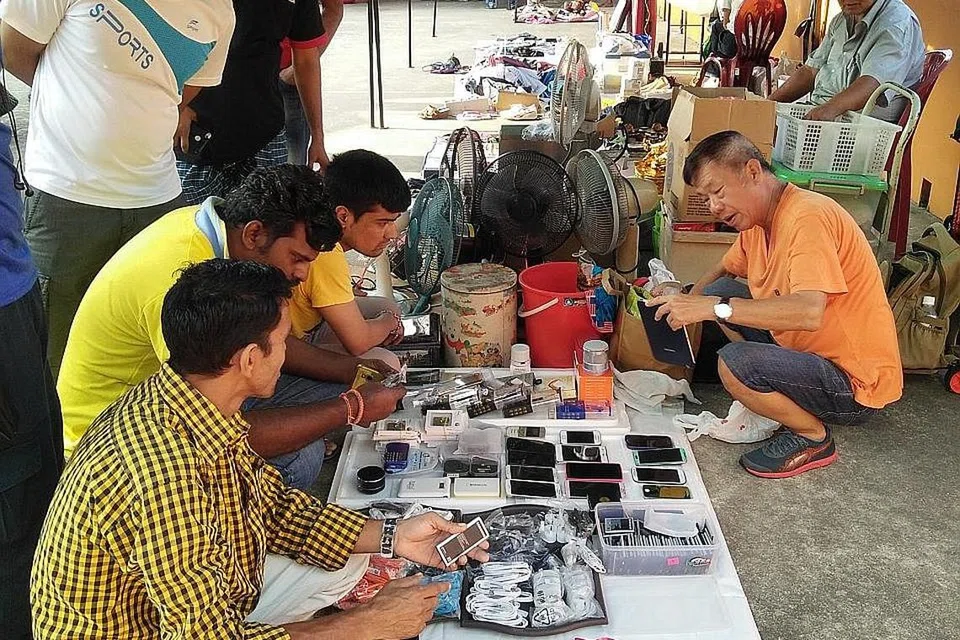 TAWAR MENAWAR: Seorang pegerai melayan pelanggan, kebanyakannya pekerja asing, yang rancak tawar-menawar ketika membeli telefon bimbit terpakai. - Foto SAINI SALLEH.