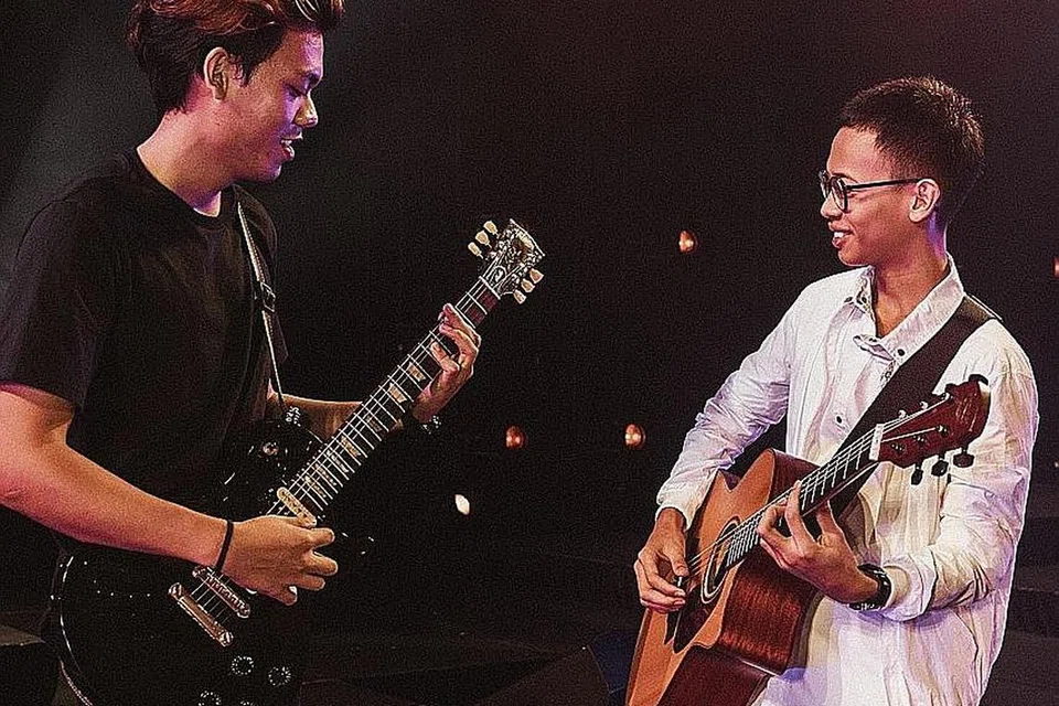 BERTUAH BELAJAR DARI LEGENDA: (Dari kiri) Encik Muhd Harashta Hasbullah dan Encik Elfie Idraki Norhaime gembira dapat menggarap kemahiran memetik gitar daripada legenda gitar setempat, Addy Cradle. - Foto BH oleh KHIDHIR ASYRAF MAHBOB