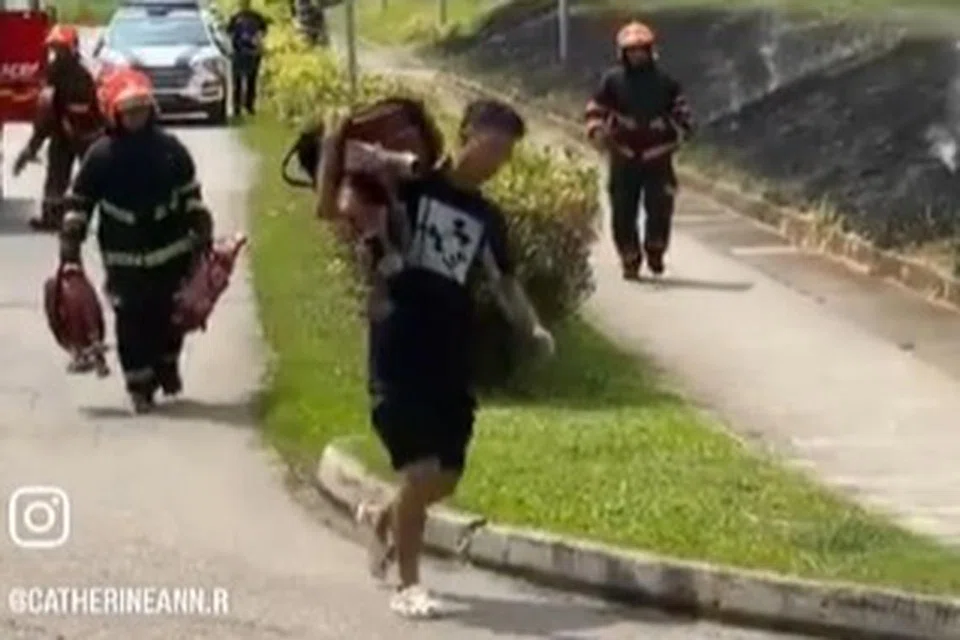 PIKUL GETAH AIR: Seorang lelaki membantu pegawai SCDF memikul getah air daripada kenderaan bomba.